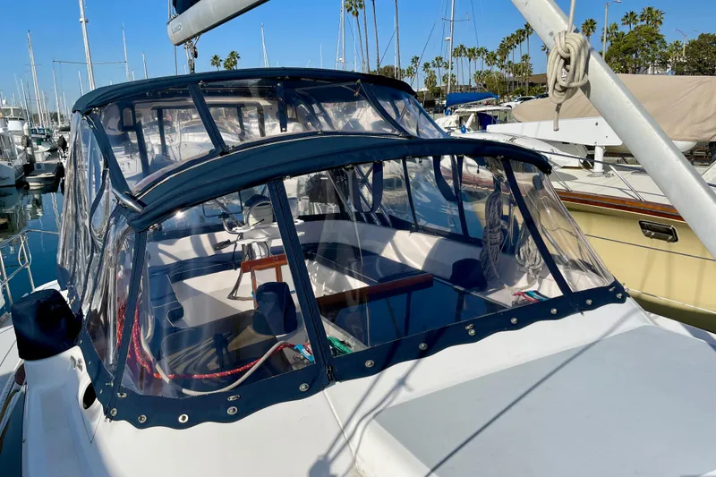 Slide: The Image of 1998 Hunter Passage 42 sailboat with clear cockpit enclosure, docked in a marina. - 15