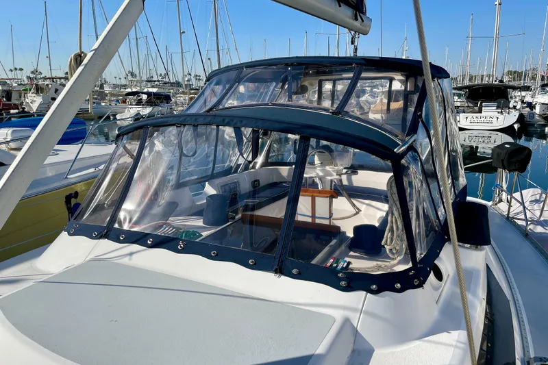 Slide: The Image of 1998 Hunter Passage 42 sailboat docked in a marina, featuring a clear cockpit enclosure. - 16