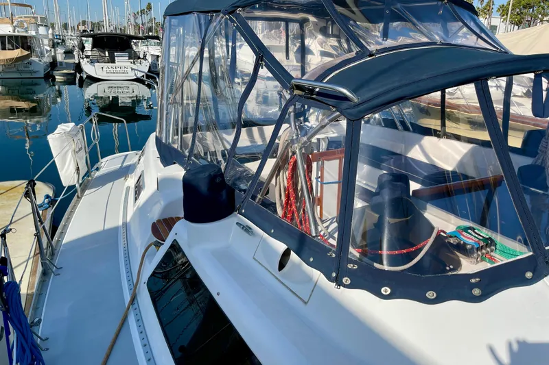 Slide: The Image of 1998 Hunter Passage 42 sailboat docked in marina, featuring clear canopy and nautical equipment. - 20
