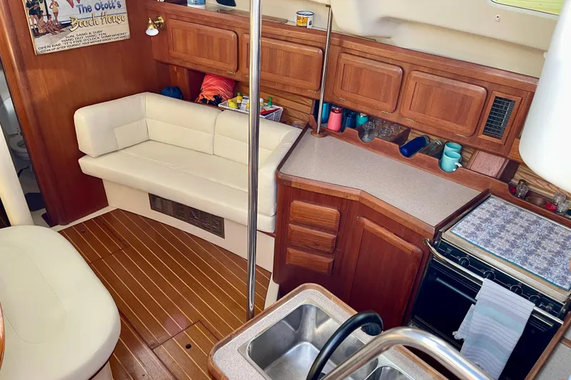Slide: The Image of 1998 Hunter Passage 42 yacht interior with wooden cabinetry, white seating, and kitchen amenities. - 31