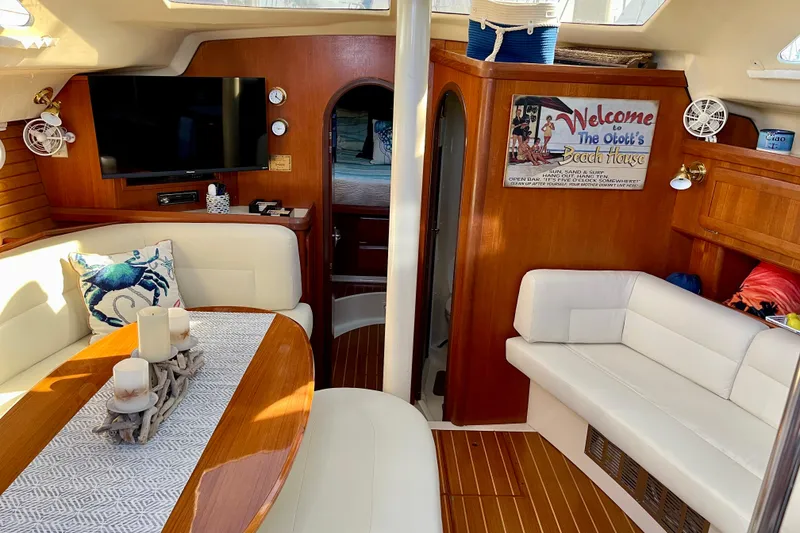 Slide: The Image of 1998 Hunter Passage 42 yacht interior with cozy seating, TV, and nautical decor. - 36