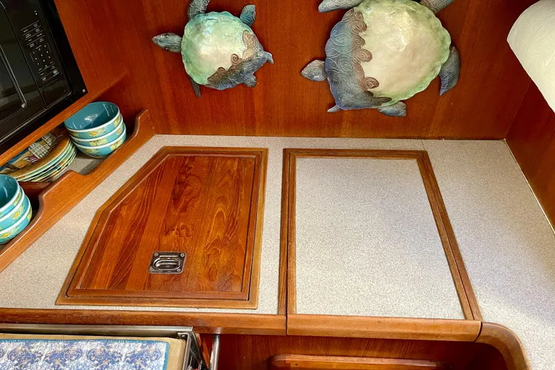 Slide: The Image of 1998 Hunter Passage 42 yacht interior with wooden cabinetry and decorative turtle wall art. - 41