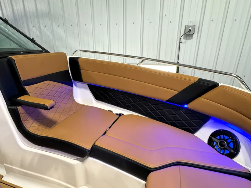 Slide: The Image of 2025 Chaparral 267 SSX boat interior with tan and black seating, blue LED lighting. - 10