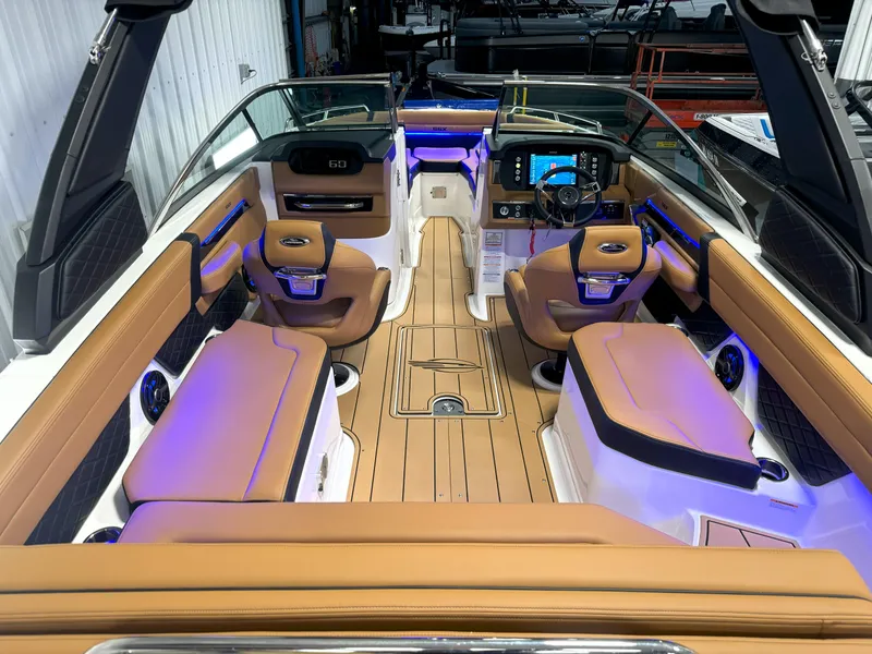 Slide: The Image of 2025 Chaparral 267 SSX boat interior with tan seating and modern dashboard. - 18