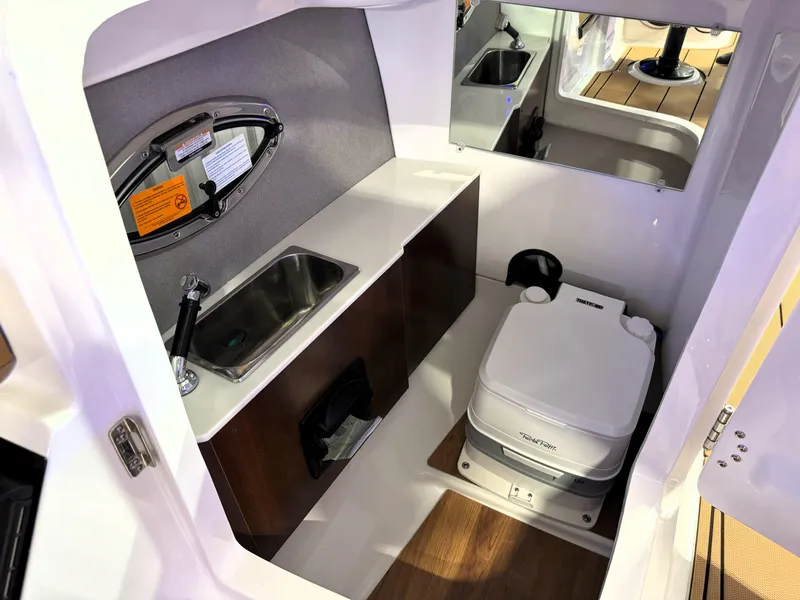 Slide: The Image of 2025 Chaparral 267 SSX boat interior with sink and toilet, featuring modern design and wood flooring. - 23
