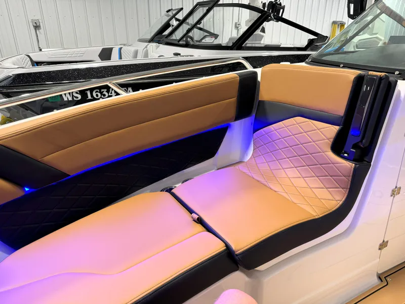 Slide: The Image of 2025 Chaparral 267 SSX boat interior with tan and black seating, blue accent lighting. - 9