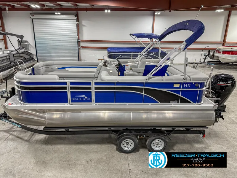 Slide: The Image of 2023 Bennington 208 SL pontoon boat in showroom, blue and silver design. - 1