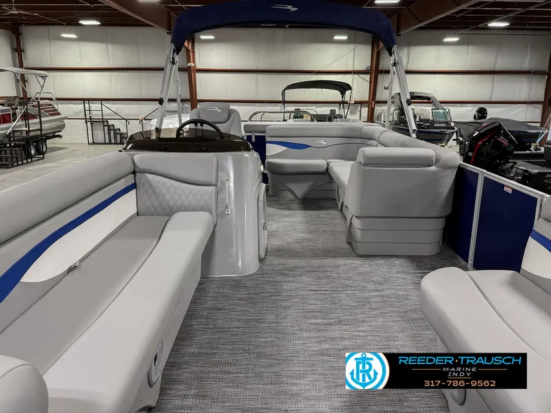 Slide: The Image of 2023 Bennington 208 SL pontoon boat interior with gray seating and blue accents in a showroom. - 16