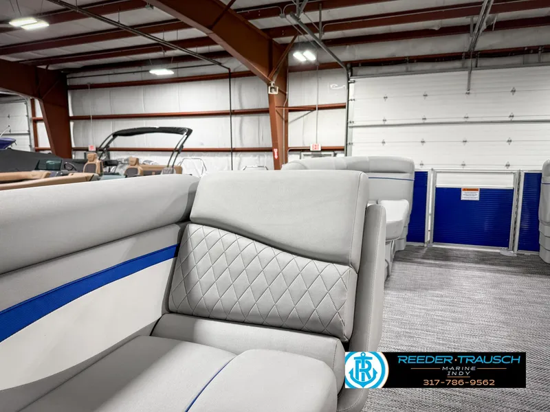 Slide: The Image of 2023 Bennington 208 SL boat interior with gray and blue seating in a showroom. - 21