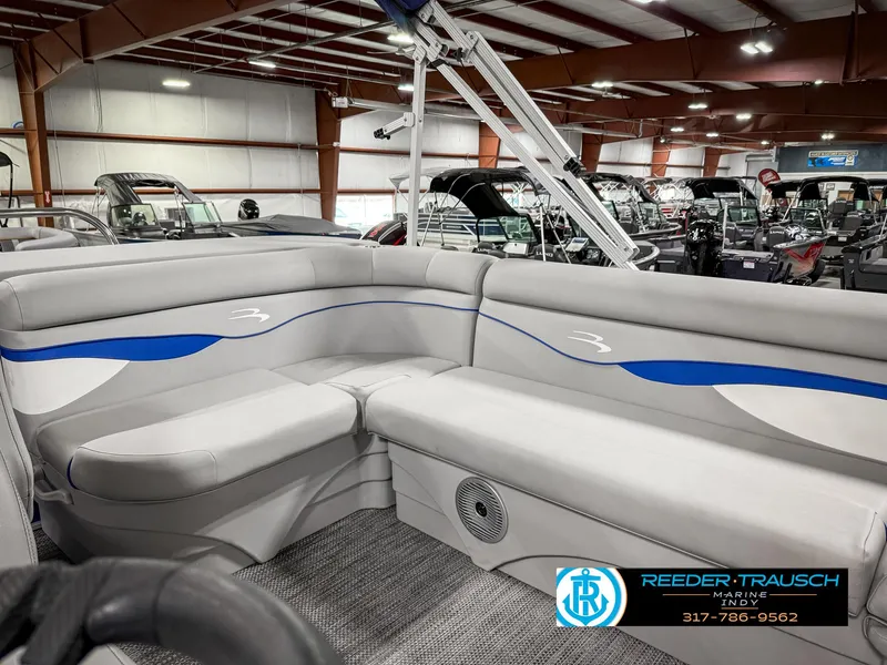 Slide: The Image of 2023 Bennington 208 SL boat interior with gray and blue seating in showroom. - 23