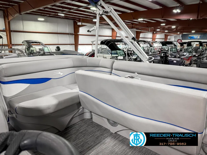 Slide: The Image of 2023 Bennington 208 SL pontoon boat interior with gray and blue seating in showroom. - 24