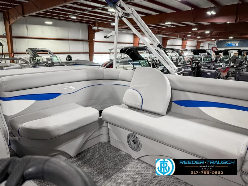 Slide: The Image of 2023 Bennington 208 SL boat interior with gray seating and blue accents in showroom. - 26