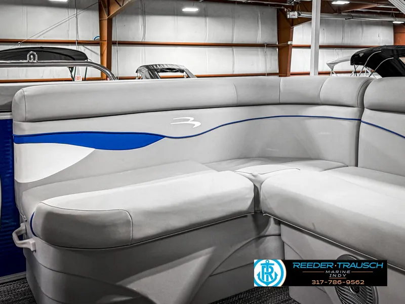 Slide: The Image of 2023 Bennington 208 SL boat interior with gray and blue seating in showroom. - 39
