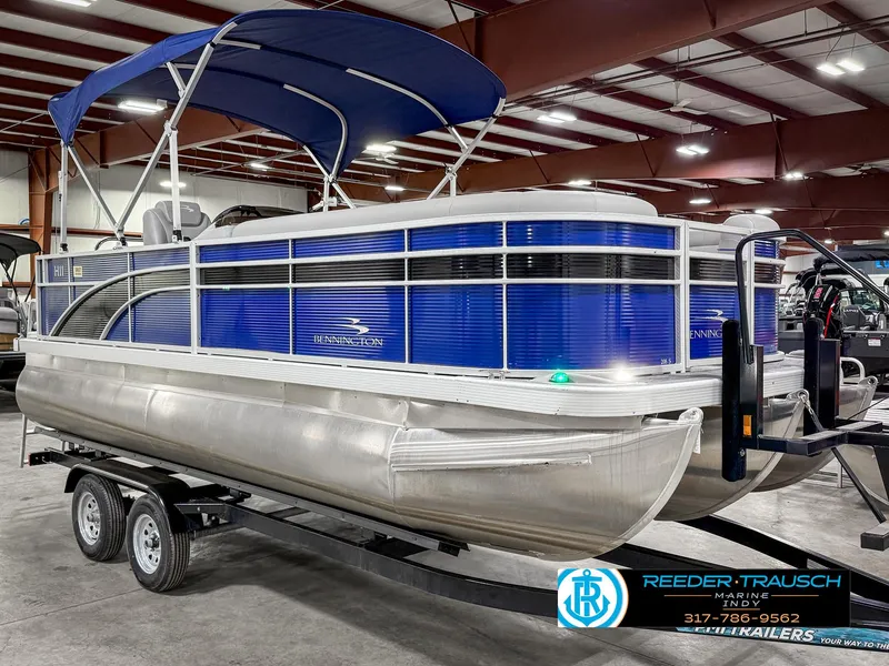 Slide: The Image of 2023 Bennington 208 SL pontoon boat with blue canopy on trailer in showroom. - 6