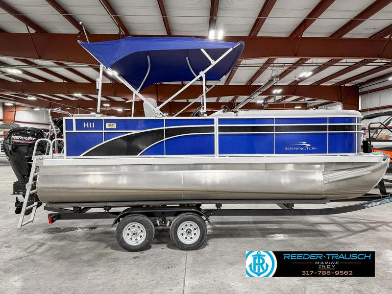 Slide: The Image of 2023 Bennington 208 SL pontoon boat with blue canopy on trailer in warehouse. - 7