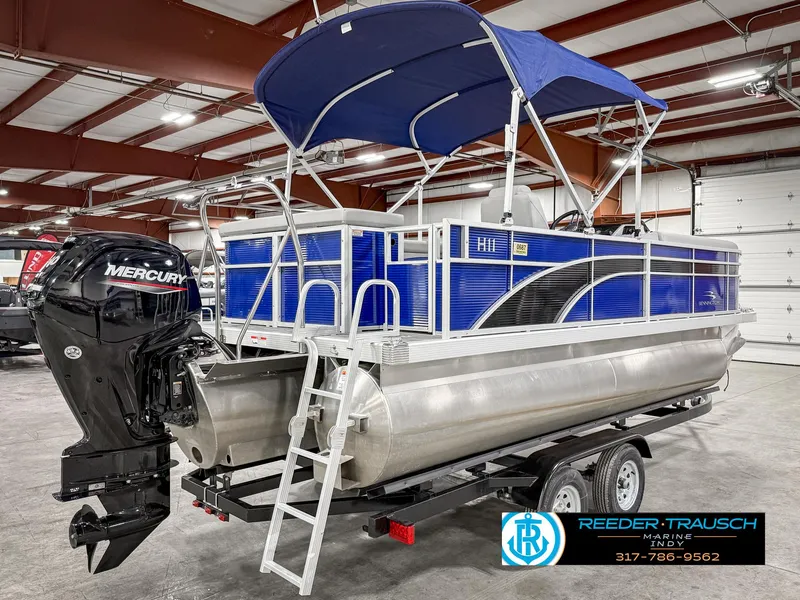 Slide: The Image of 2023 Bennington 208 SL pontoon boat with blue canopy and Mercury outboard motor in showroom. - 8