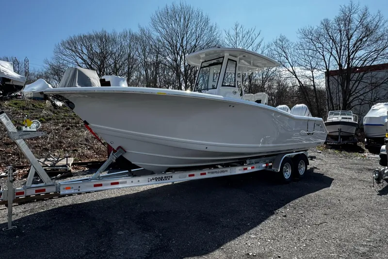 Slide: The Image of 2025 Tidewater 282 CC Adventure boat on trailer, parked outdoors. - 2