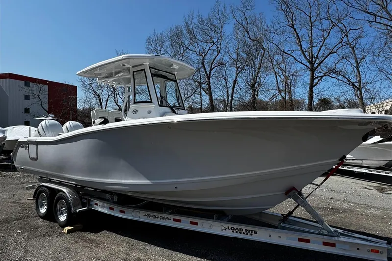Slide: The Image of 2025 Tidewater 282 CC Adventure boat on trailer, parked outdoors under clear blue sky. - 4