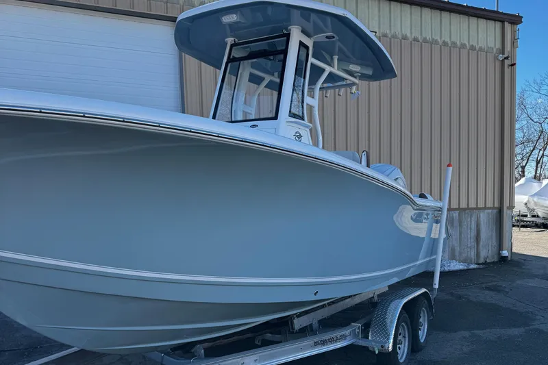 Slide: The Image of 2025 Tidewater 232 LXF boat on trailer, parked outside a warehouse. - 4