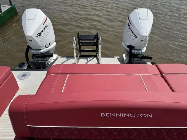 Slide: The Image of 2025 Bennington QX Swingback 30 QXSBWAX2 boat with red seating, on a calm lake. - 5
