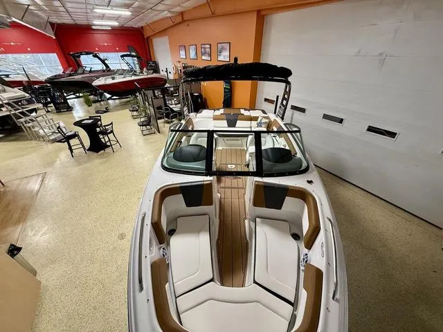 Slide: The Image of 2025 Chaparral 23 SSi boat in showroom, featuring sleek design and spacious seating. - 16