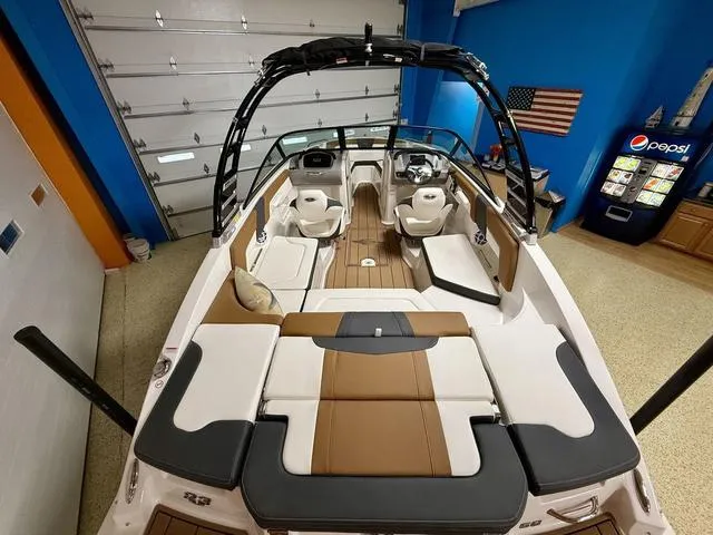 Slide: The Image of 2025 Chaparral 23 SSi boat interior with modern seating and sleek design in a showroom. - 5