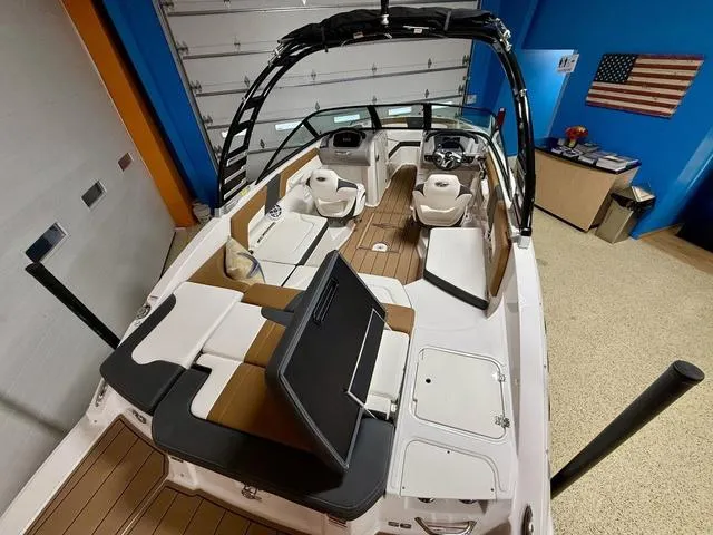 Slide: The Image of 2025 Chaparral 23 SSi boat interior with seating and helm, in a showroom setting. - 7