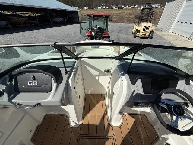 Slide: The Image of 2025 Chaparral 23 SSi boat interior with steering wheel and dashboard, parked near tractors. - 15