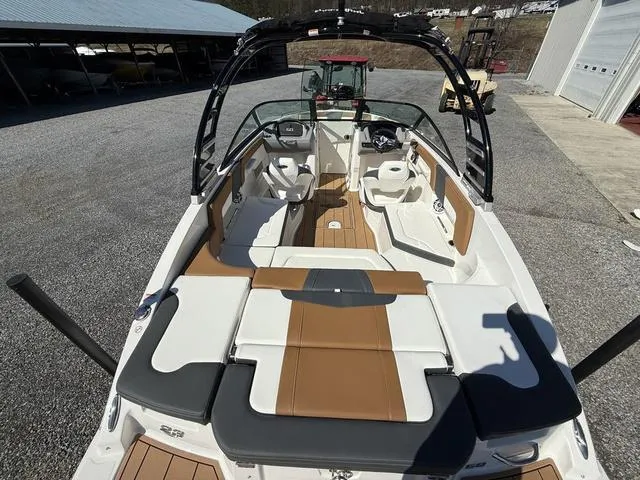 Slide: The Image of 2025 Chaparral 23 SSi boat interior with tan and white seating, docked outdoors. - 6