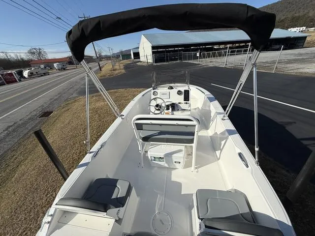 Slide: The Image of 2025 Robalo R160 boat with canopy, white interior, and dual seating, parked near a road. - 6