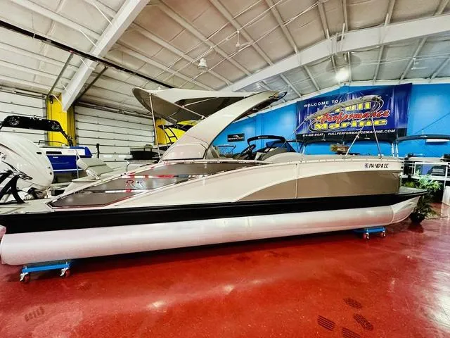 Slide: The Image of 2023 Bennington 25 RXSBA pontoon boat displayed indoors on a red floor. - 5