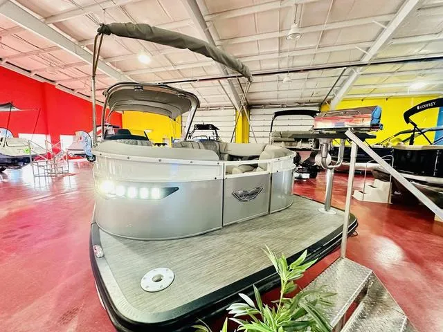 Slide: The Image of 2023 Bennington 25 RXSBA pontoon boat displayed in a showroom with vibrant red and yellow walls. - 9