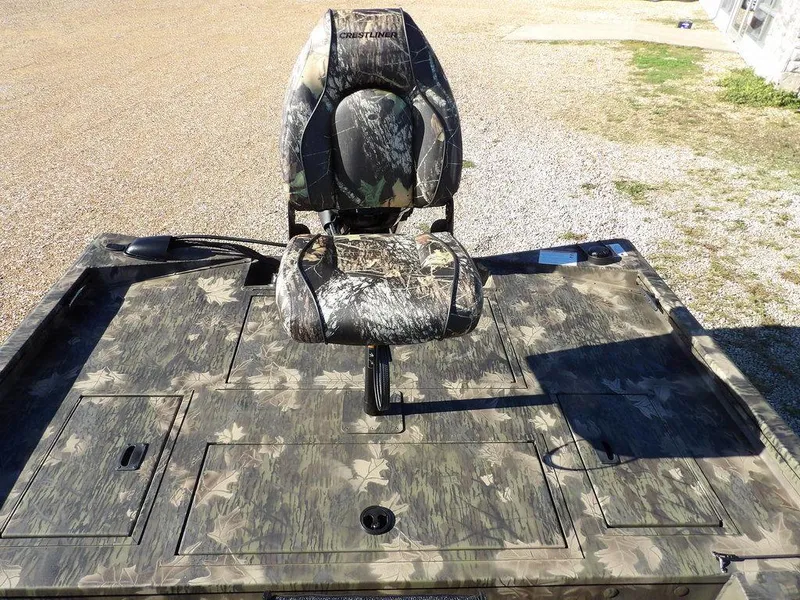 Slide: The Image of 2025 Crestliner XFC 189 boat with camo seat and deck, parked on gravel. - 11