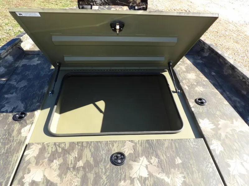 Slide: The Image of 2025 Crestliner XFC 189 boat storage compartment with open lid, camo design. - 25