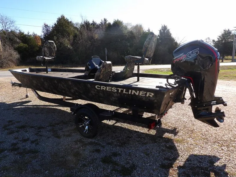Slide: The Image of 2025 Crestliner XFC 189 boat with motor, parked on gravel, surrounded by trees. - 5