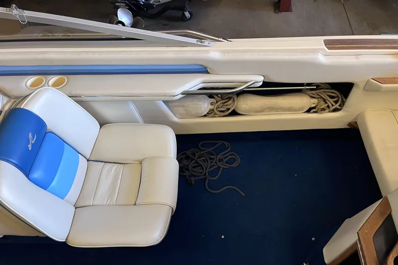 Slide: The Image of 1987 Sea Ray 23 Sorrento interior with blue and white seating, ropes, and storage compartment. - 15