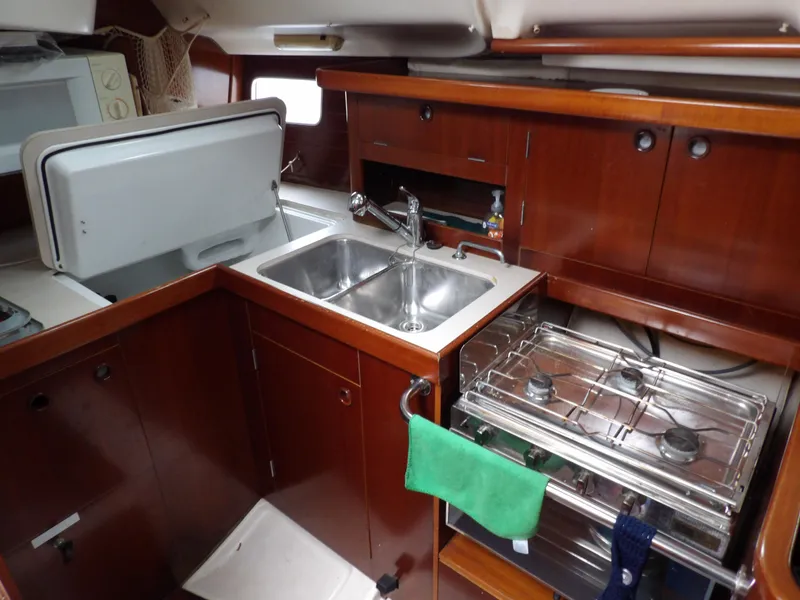 Slide: The Image of 1994 Beneteau Oceanis 351 yacht kitchen with sink, stove, and wooden cabinetry. - 32