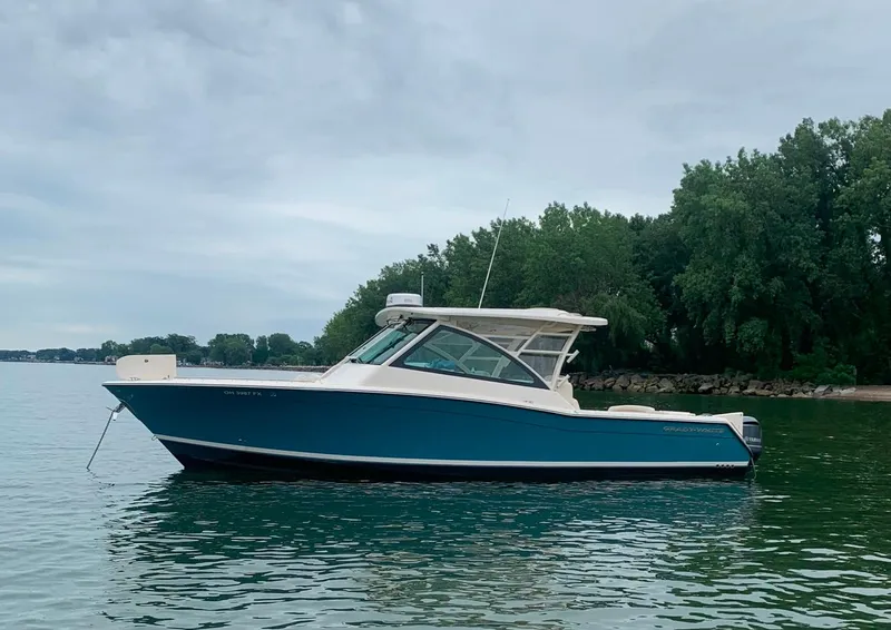 Slide: The Image of 2019 Grady-White Freedom 375 boat on calm water near a wooded shoreline. - 17