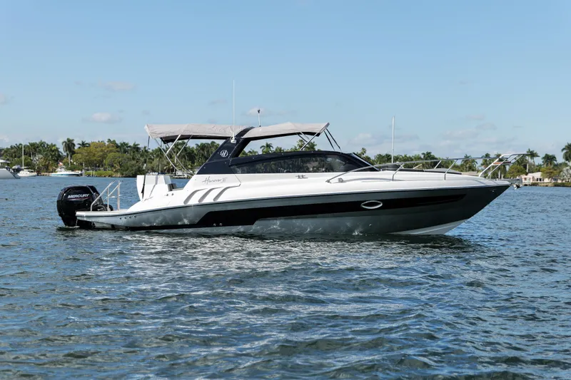 Slide: The Image of 2025 Hanover 305 Outboard Alpine Gray Ultimate Sport Edition boat on water. - 9
