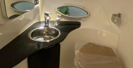 Slide: The Image of 2025 Hanover 305 Outboard T-Top Edition interior with sink and porthole window. - 12