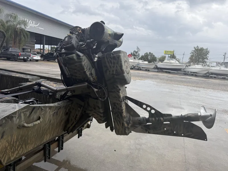 Slide: The Image of 2005 Gator Trax 18 boat with camo design, parked near a boatyard. - 2
