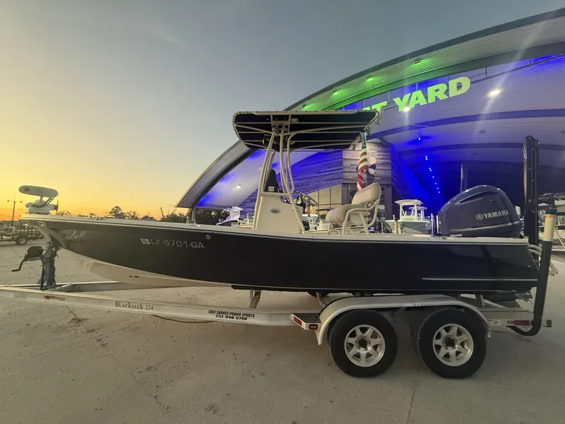 Slide: The Image of 2013 BlackJack 224 boat on trailer at sunset, parked outside a lit building. - 7