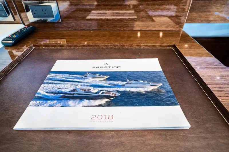 Slide: The Image of Brochure of Prestige 630 yacht, 2018 edition, on a wooden table. - 43