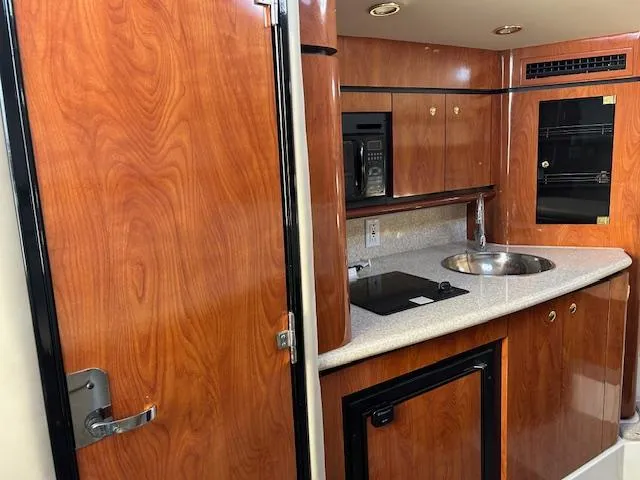 Slide: The Image of 2008 Fountain 38 Sportfish Express Cruiser interior with wood cabinetry and compact kitchen amenities. - 29