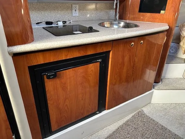 Slide: The Image of 2008 Fountain 38 Sportfish Express Cruiser kitchen with wood cabinets, sink, and mini fridge. - 35