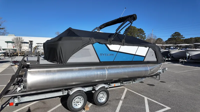 Slide: The Image of 2025 Sylvan A-Series A20 LZ DH pontoon boat on trailer, covered, in parking lot. - 15