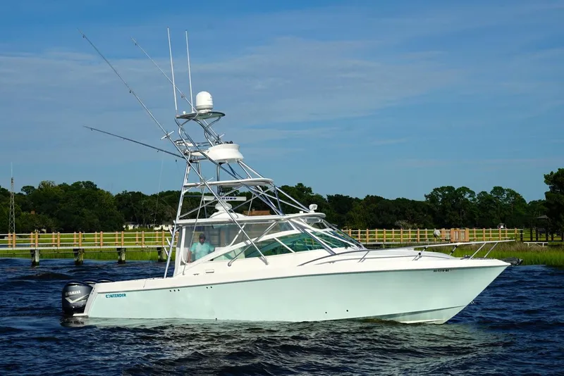 Slide: The Image of 2009 Contender 38 Express boat with triple Yamaha engines on a scenic waterway. - 1