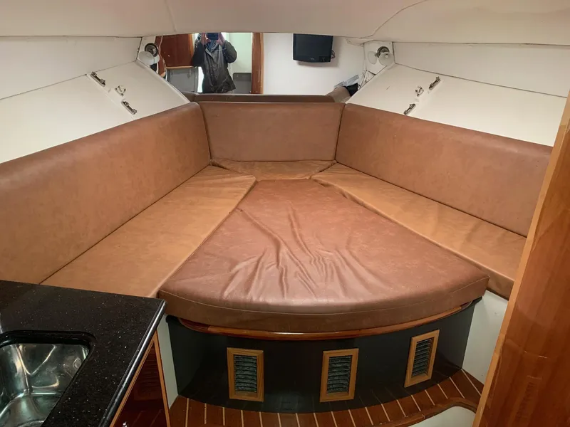 Slide: The Image of 2009 Contender 38 Express cabin interior with brown leather seating and compact kitchenette. - 18