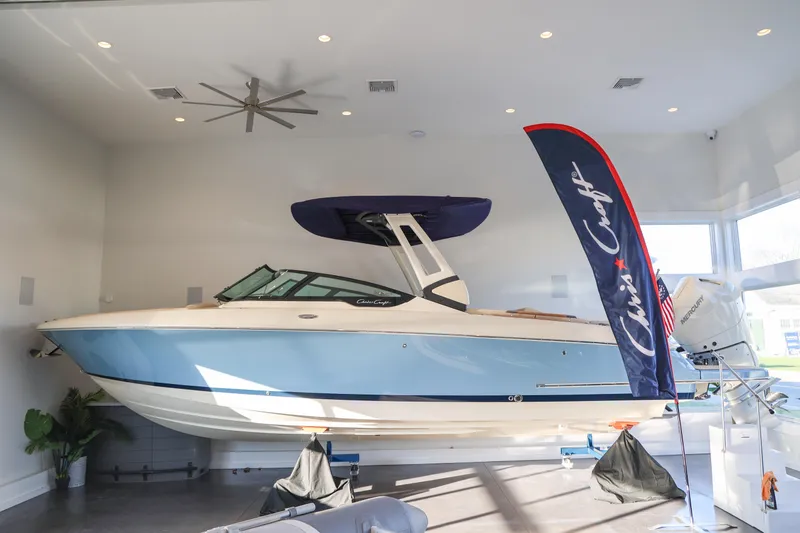 The Image of 2026 Chris-Craft Sportster 28 boat in showroom with flag. - 0