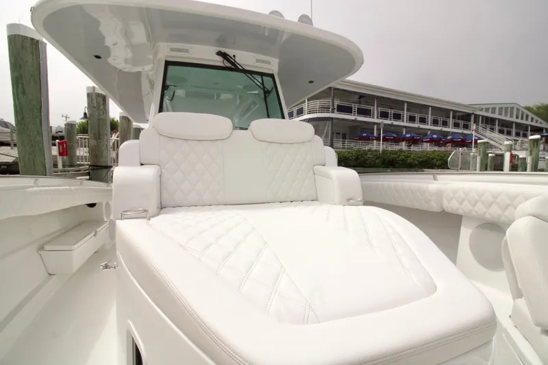 Slide: The Image of Luxurious white seating on 2026 HCB 42 Lujo boat, docked near a waterfront building. - 20